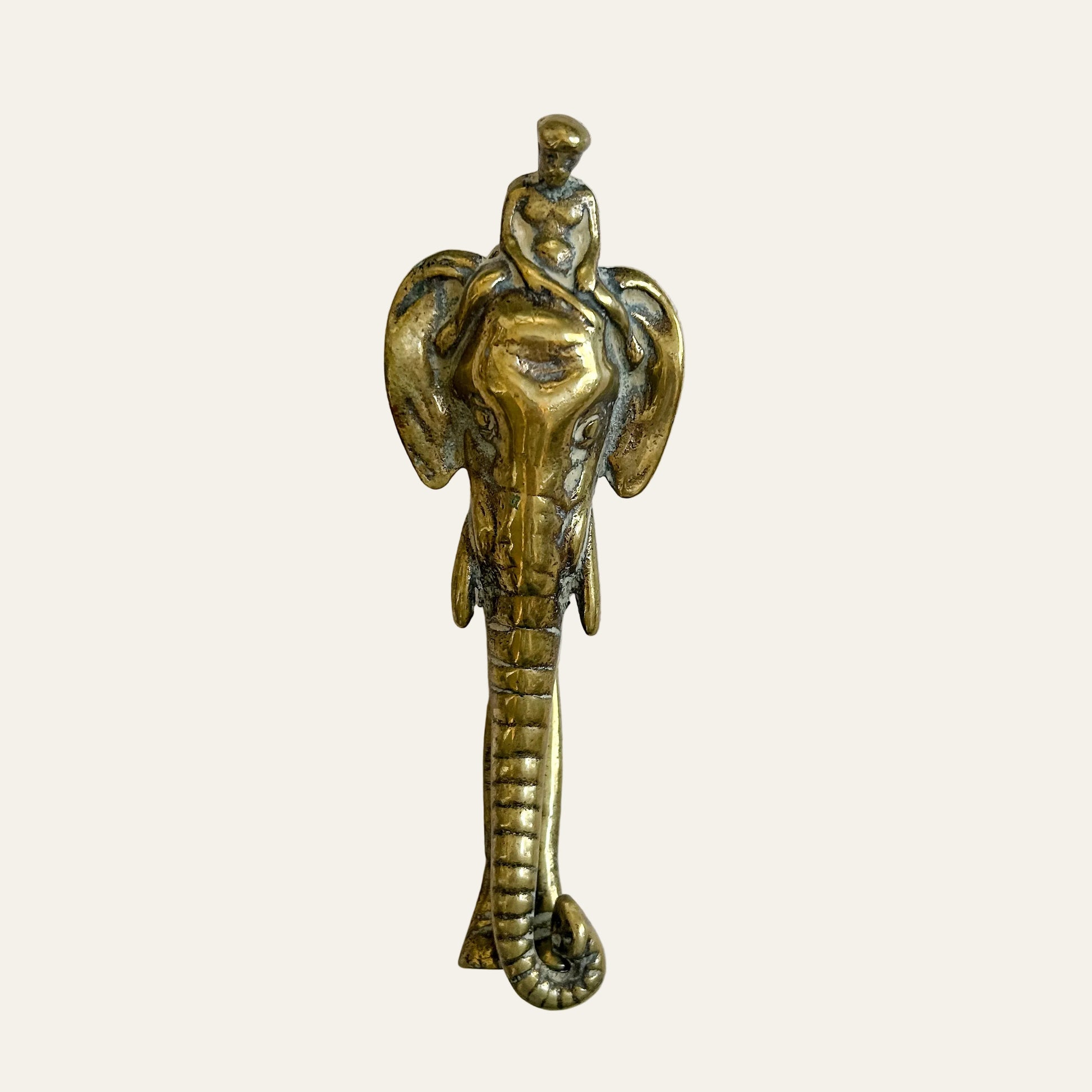 Bronze snake-shaped object with a figure on a beige background