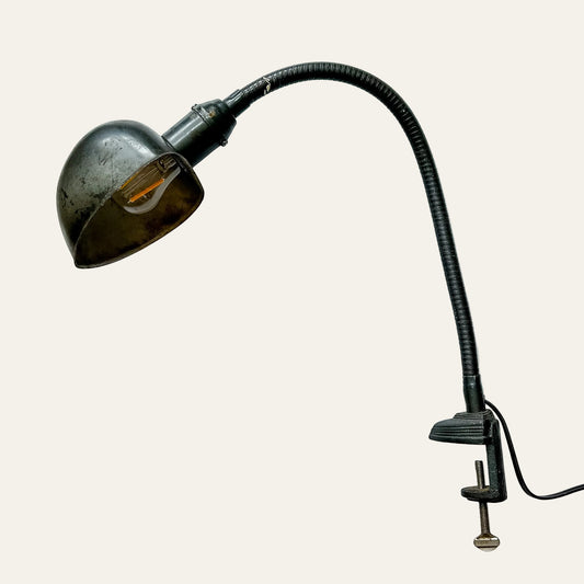 Vintage-style wall lamp with flexible neck and clamp on a textured white background