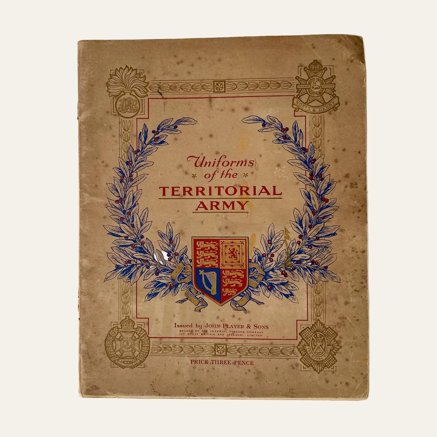 Book titled 'Uniforms of the Territorial Army' with decorative elements on a textured white background