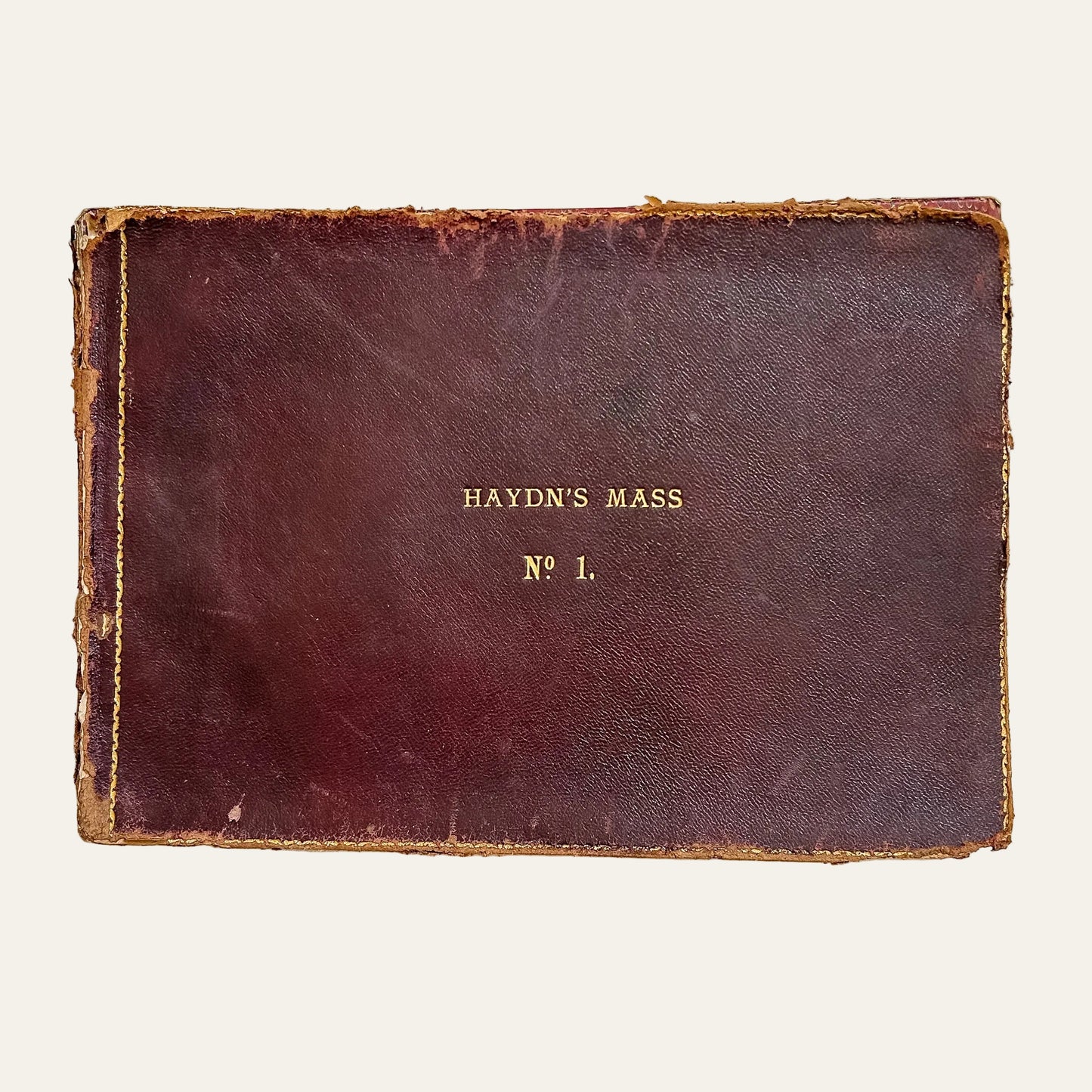 Vintage leather-bound book titled 'Haydn's Mass No. 1' on a textured white background