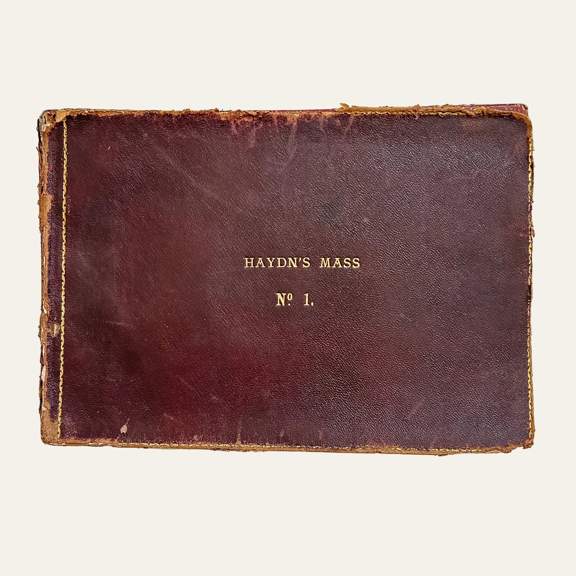 Vintage leather-bound book titled 'Haydn's Mass No. 1' on a textured white background