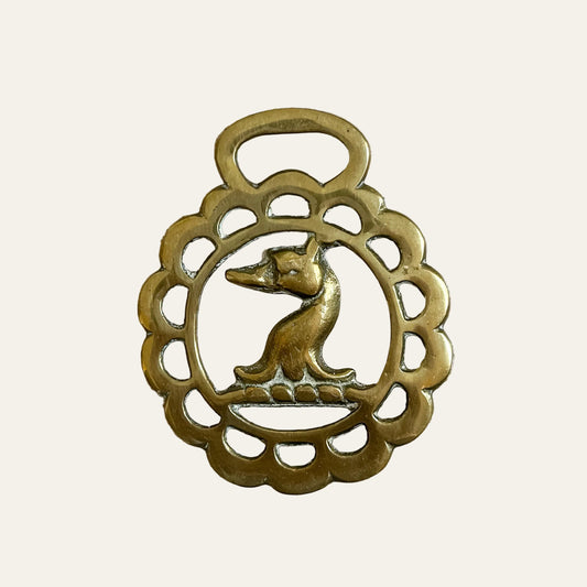 Bronze pendant with a fox design on a textured beige background