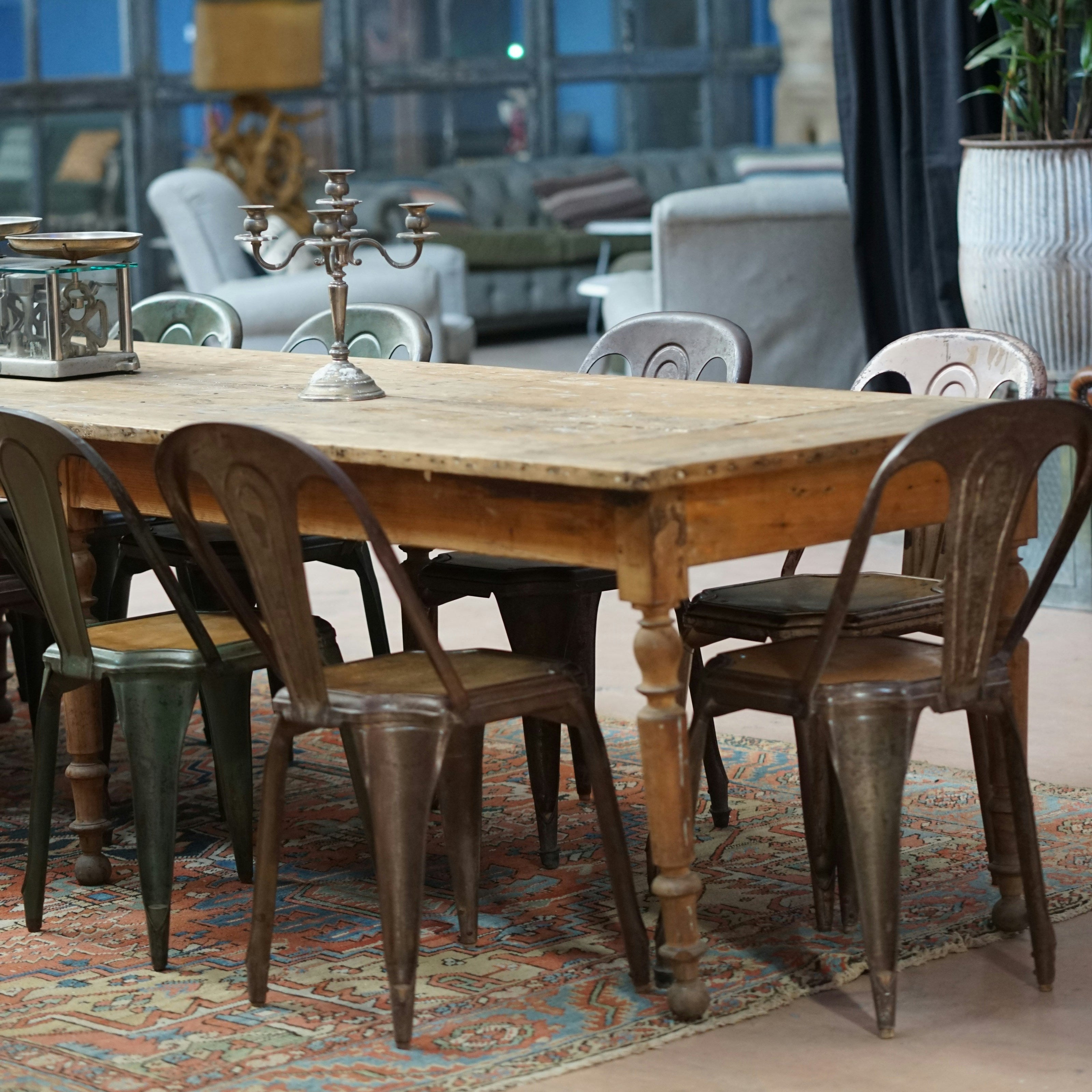 Wooden dining table with chairs in a room with large windows and decorative elements.