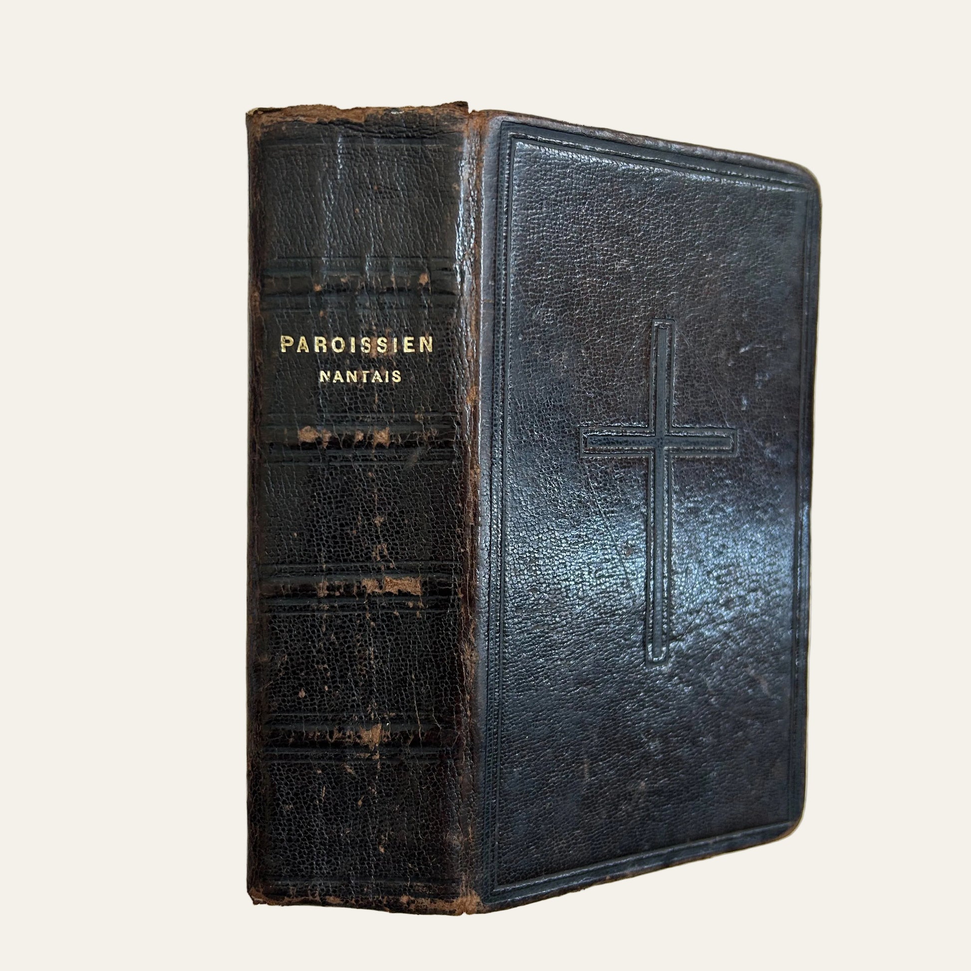 Vintage leather-bound book with a cross embossed on the cover, on a textured surface.
