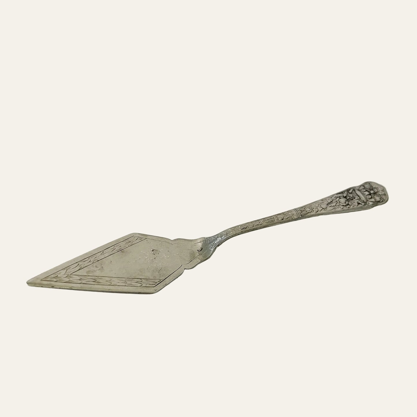 Decorative silver cake server on a light gray surface