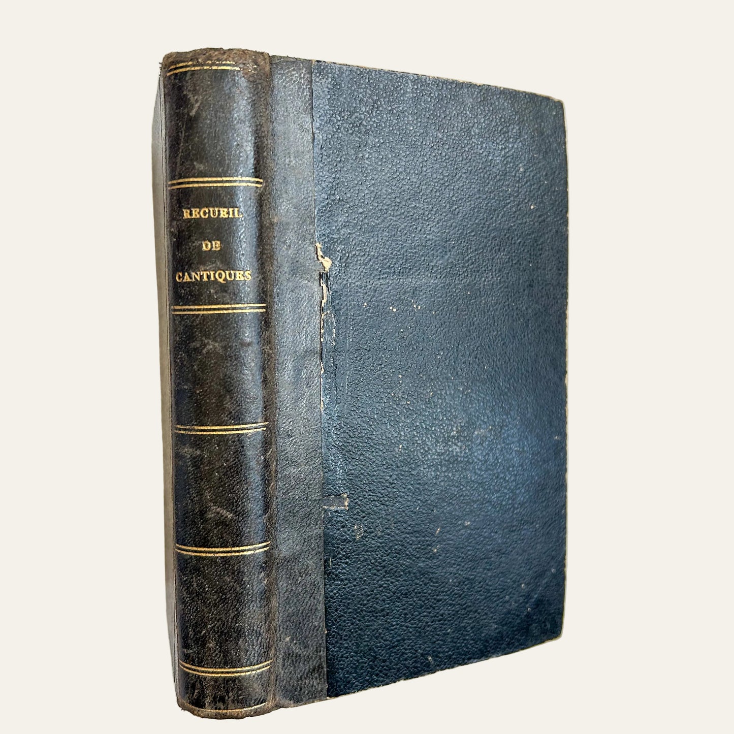 Vintage book with black leather cover and gold text on a textured beige surface